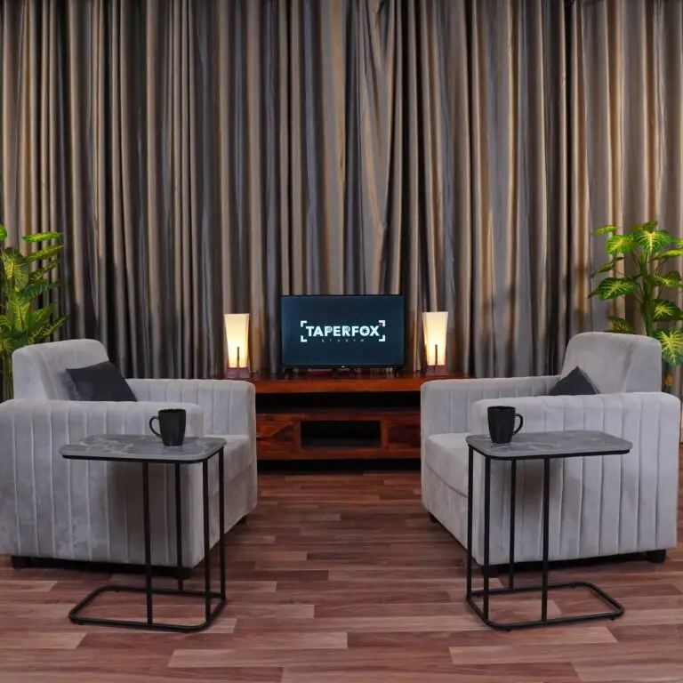 Podcast setup with grey curtains and grey sofa with warm lighting