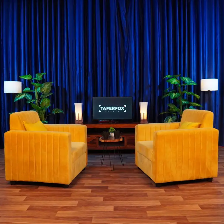 Vibrant Podcast studio setup, with yellow sofa and blue curtain background.