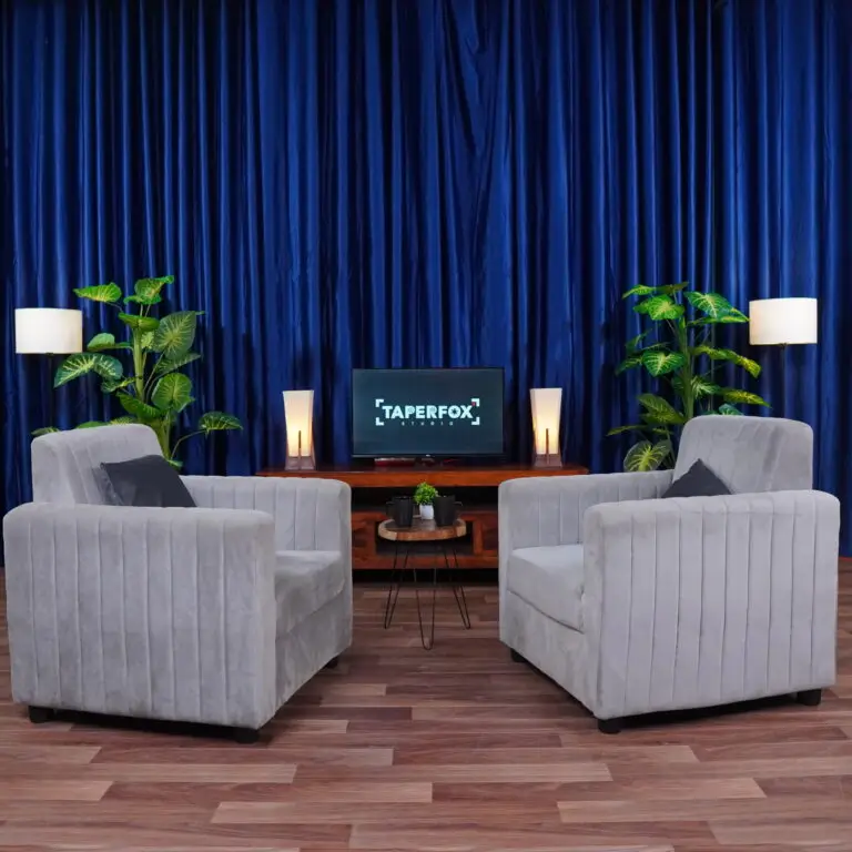 Dynamic podcast setup with grey sofa and blue curtains