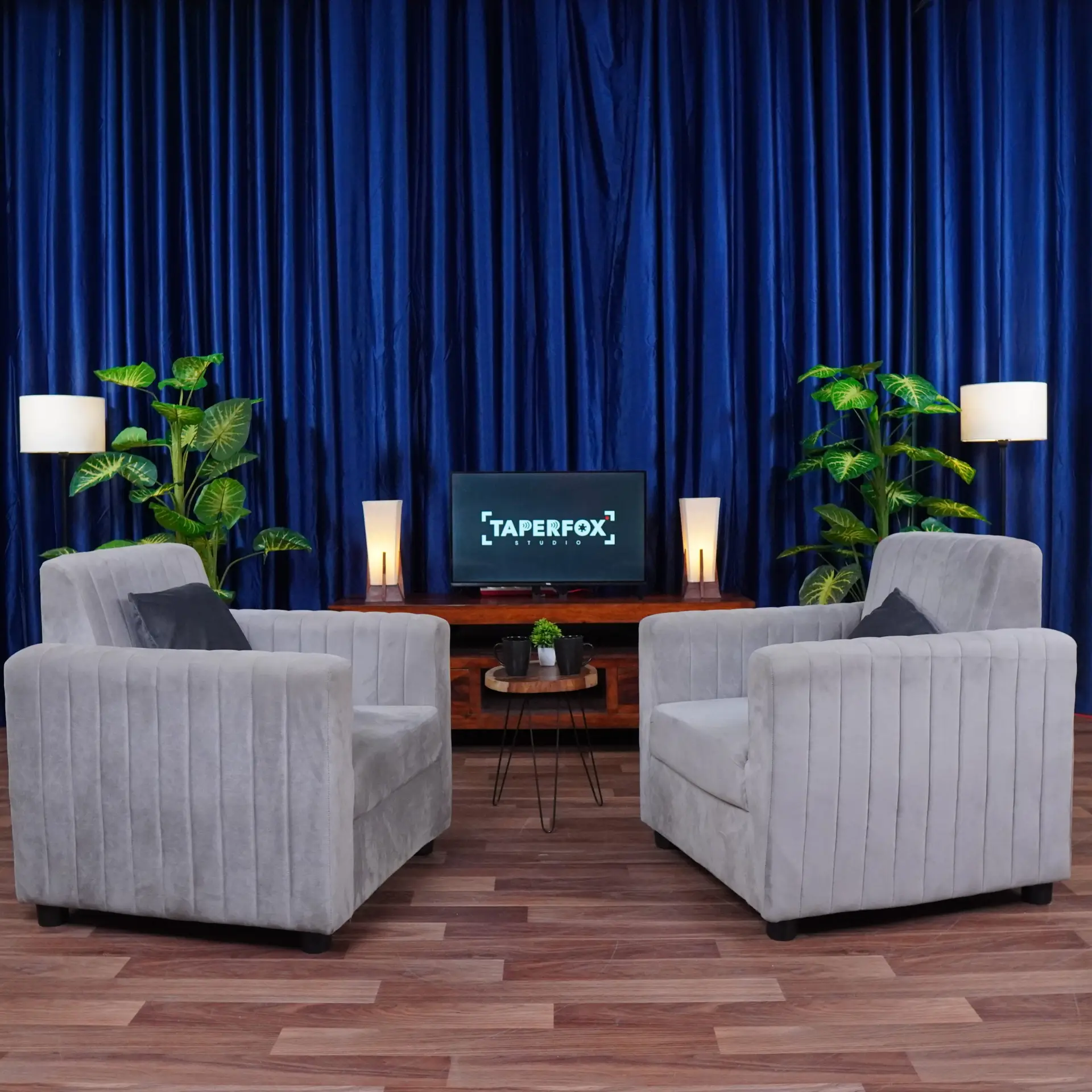 Dynamic podcast setup with grey sofa and blue curtains