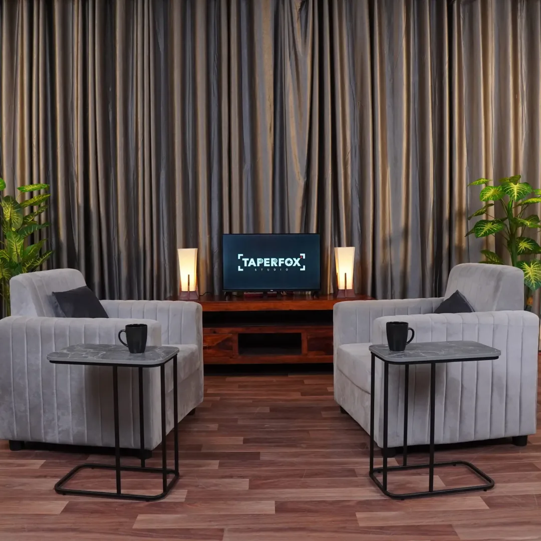 Podcast setup with grey curtains and grey sofa with warm lighting