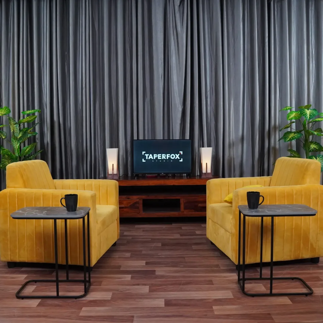 A Grey curtains with two yellow sofa and coffee table for a business podcast setup