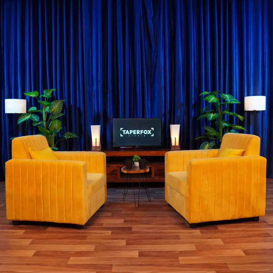 Vibrant Podcast studio setup, with yellow sofa and blue curtain background.