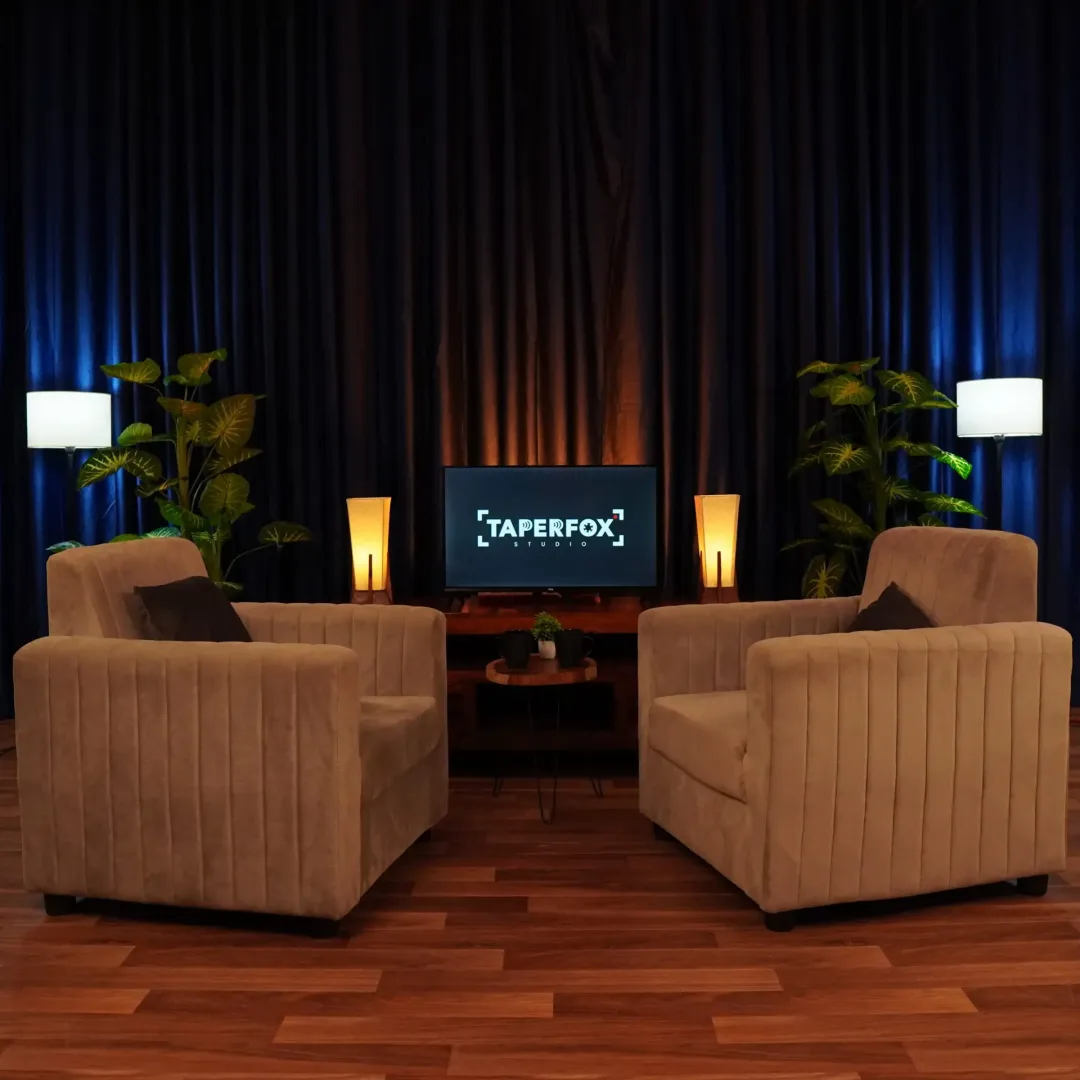 Warm looking podcast studio setup with tv and lamp